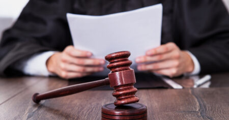 image-close-up-of-male-judge-in-front-of-mallet-holding-documents